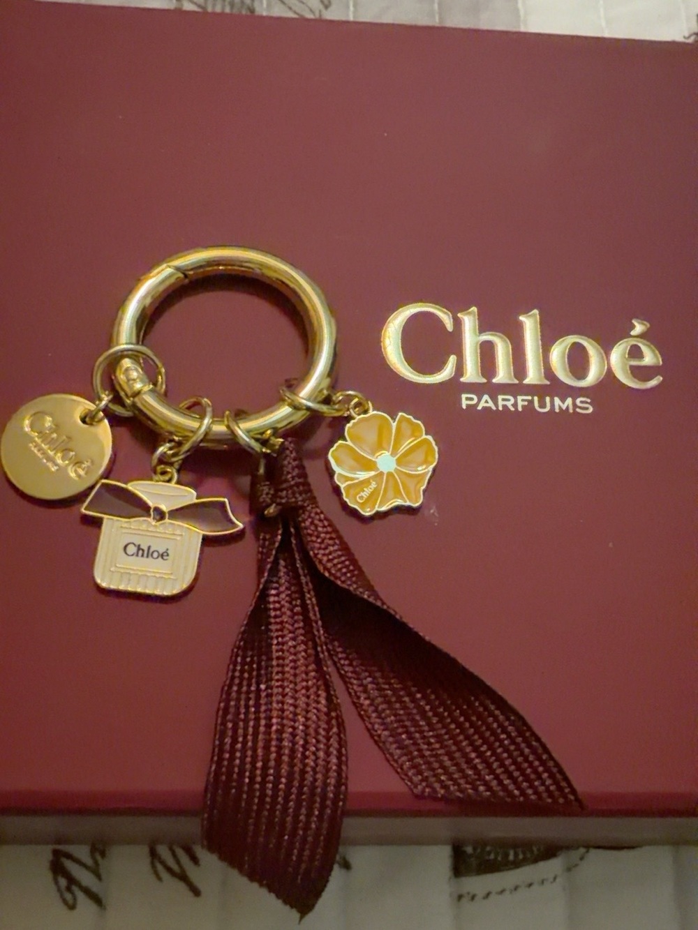 Chloé Burgundy Ribbon Charm Keyring with Gold Accents and Floral Charm